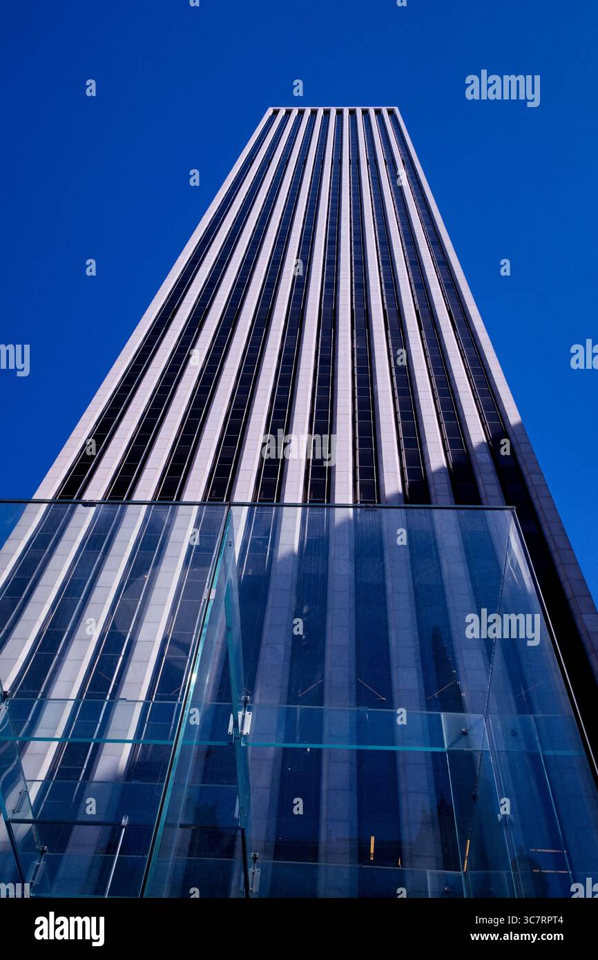 Un distintivo grattacielo a strisce nel centro di Manhattan si innalza sopra una lobby di vetro traslucido, con la sua facciata in pietra lucida adagiata su un cielo blu chiaro. Foto Stock Un distintivo grattacielo a strisce nel centro di Manhattan si innalza sopra una lobby di vetro traslucido, con la sua facciata in pietra lucida adagiata su un cielo blu chiaro. Foto Stock