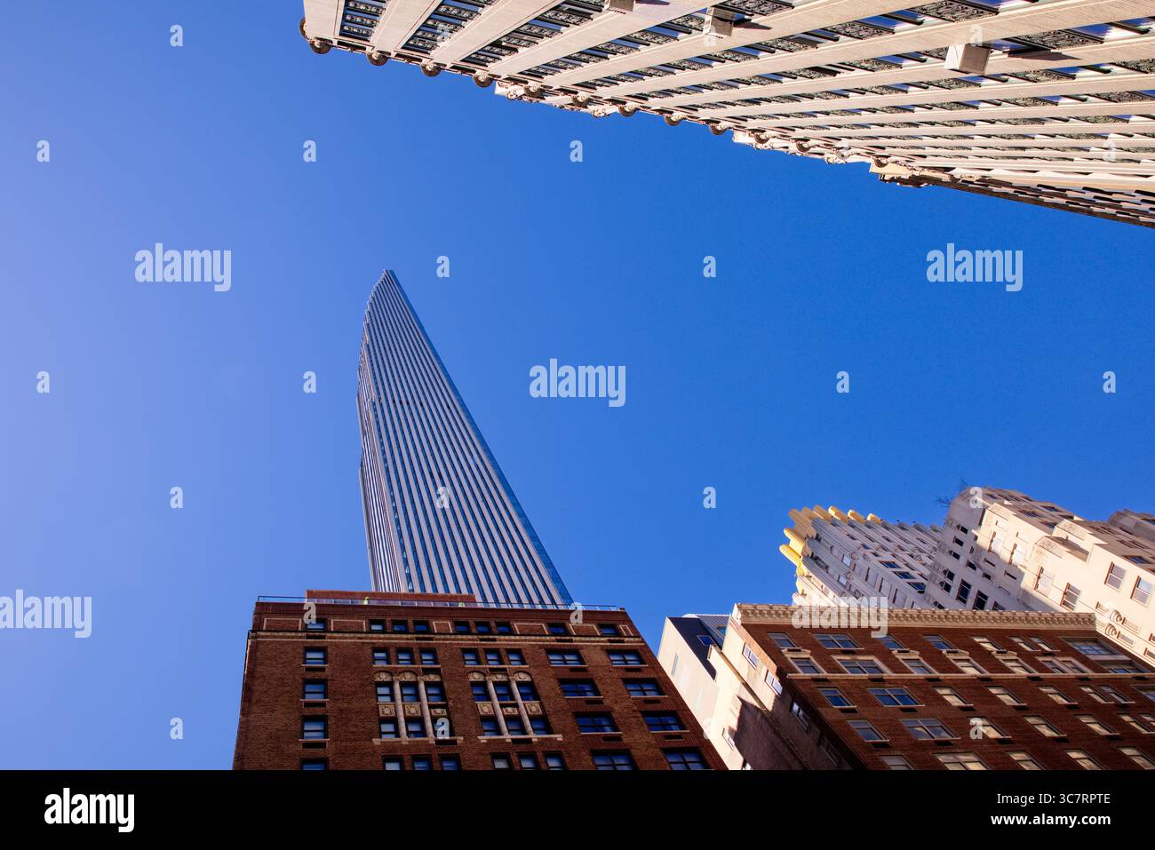 Una sottile guglia in vetro e acciaio sale sopra le storiche facciate in mattoni nel centro di Manhattan, le sue linee verticali contrastano con i vicini testurizzati. Foto Stock