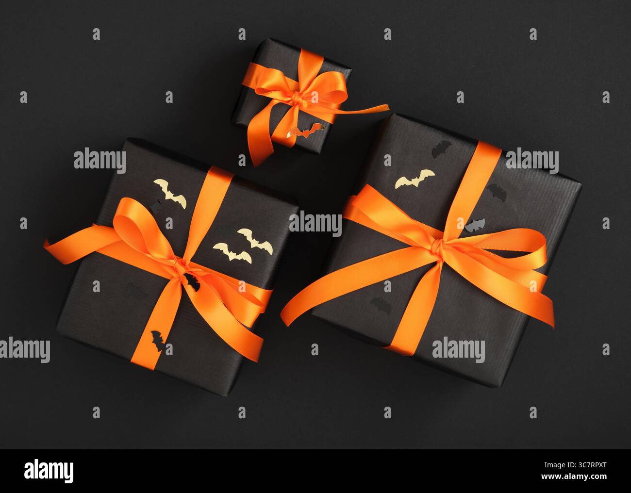 Scatole regalo nere con nastri arancioni e coriandoli a forma di pipistrello. Regali di Halloween Foto Stock