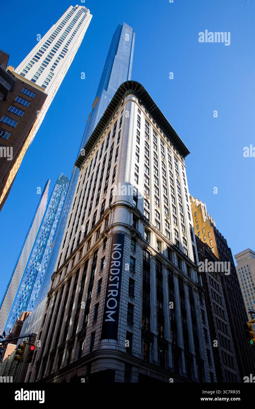 L'elegante facciata di punta di Nordstrom alla 57th Street di Midtown Manhattan è fiancheggiata da torri di vetro superalte, incorniciate da un cielo azzurro luminoso. Foto Stock