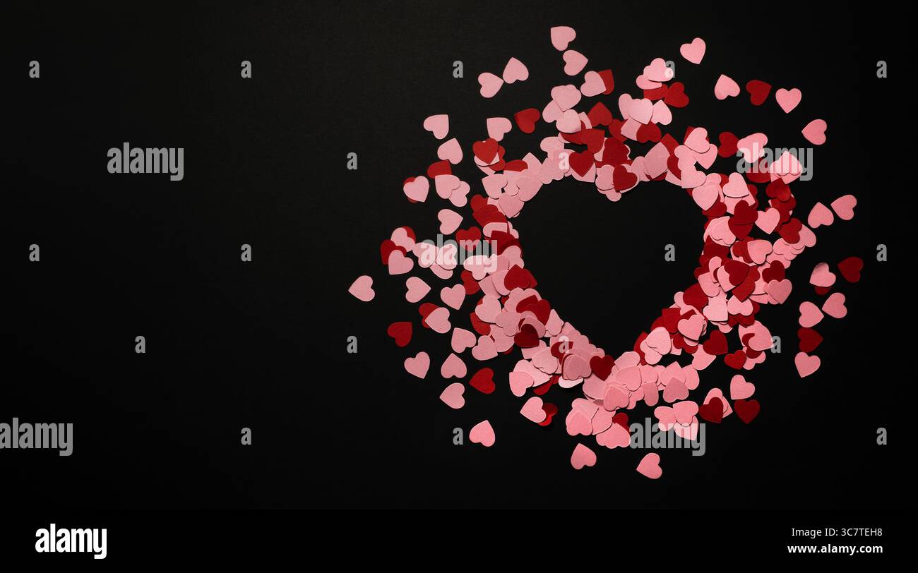 Striscione con cuore di piccola carta, cuori rossi e rosa. Copyspace, sfondo nero. Biglietto di San Valentino Foto Stock