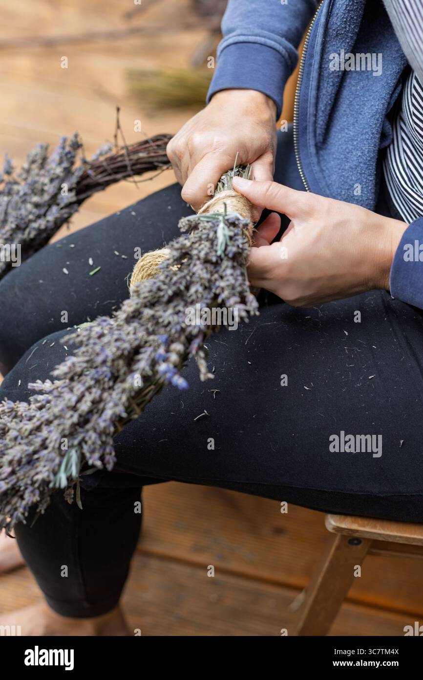 Primo piano di una donna che lega Lavender Wreath Foto Stock
