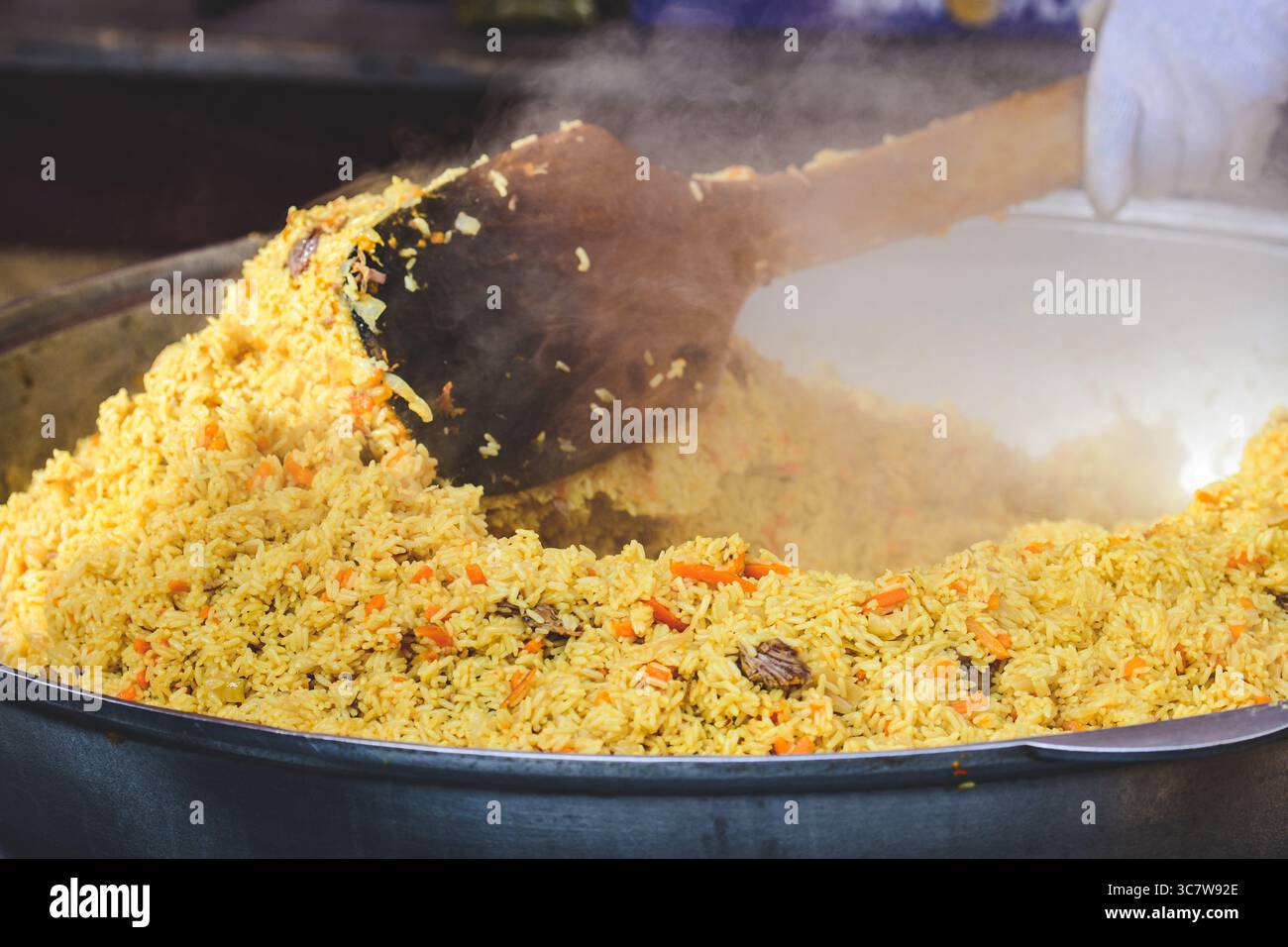 Preparazione del pilaf di riso, un piatto saporito a base di riso a grani lunghi cotto in brodo stagionato, carne di agnello e mescolato con verdure, erbe aromatiche e spezie Foto Stock