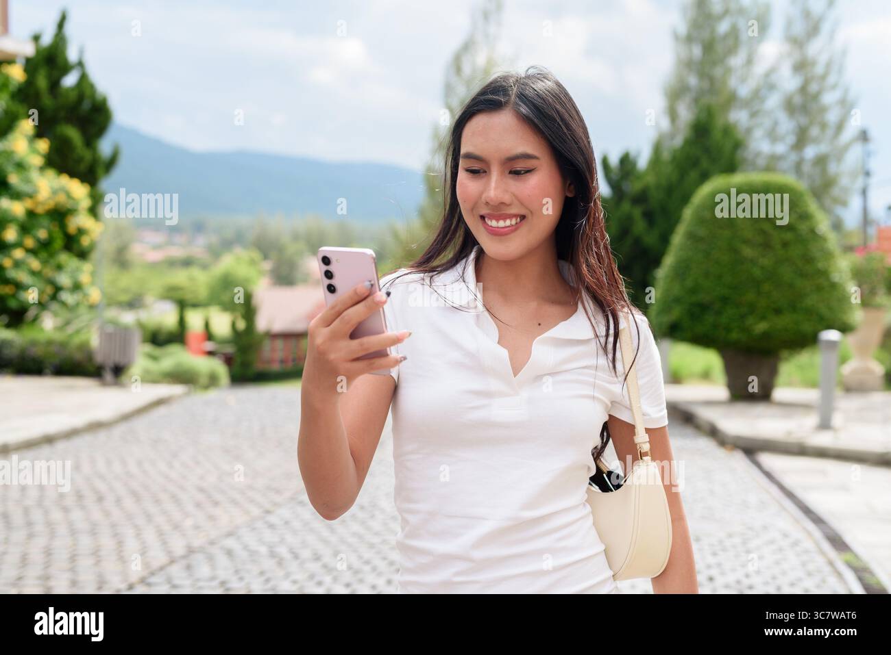 Bella giovane donna asiatica in una polo che cammina lungo la vecchia strada in stile europeo. Elegante ritratto di viaggio circondato da architettura, ad esempio naturale Foto Stock