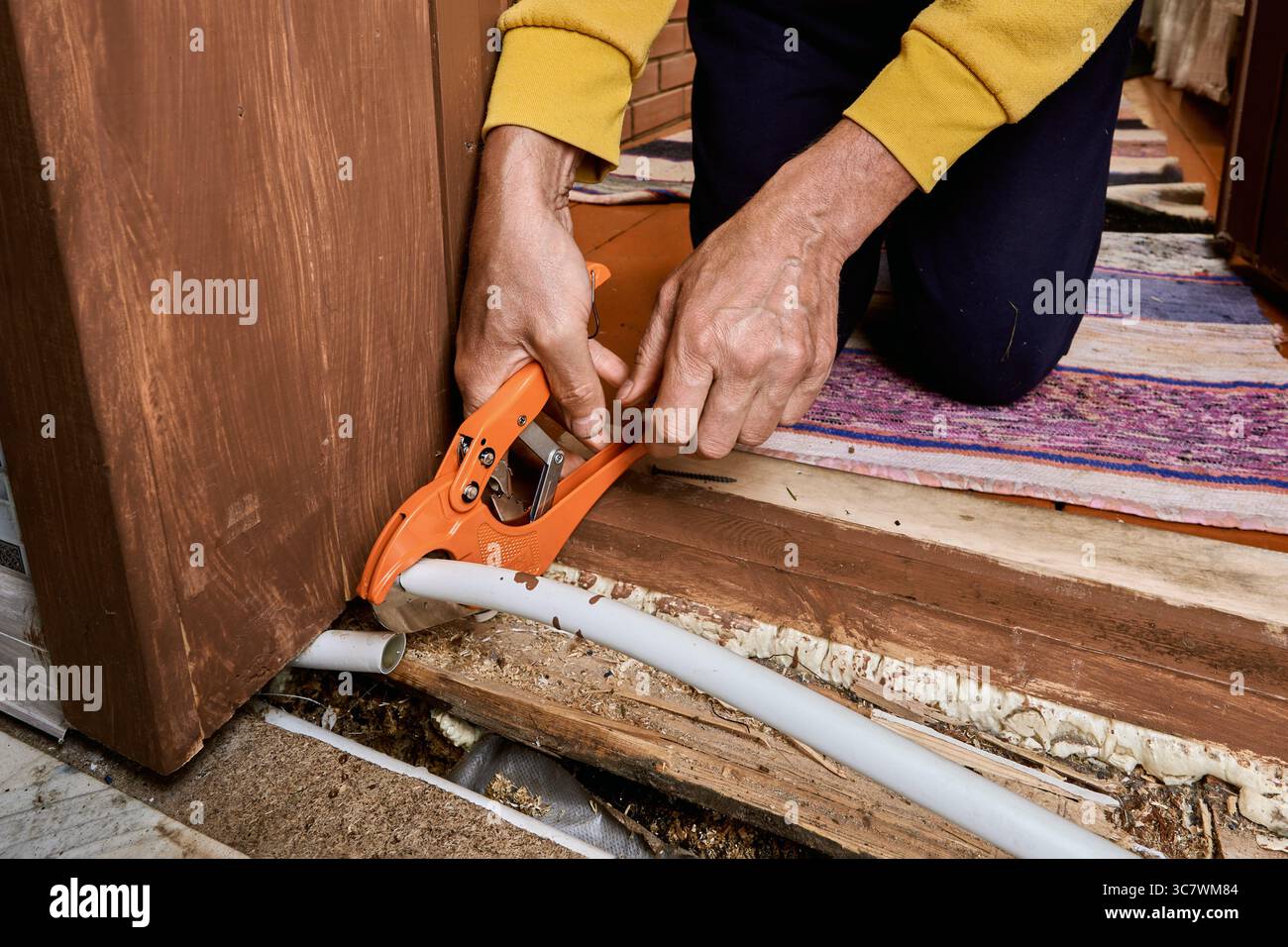 Il frammento danneggiato del tubo polimerico viene tagliato dall'idraulico che prepara lo spazio di installazione per il collegamento di un nuovo pezzo per ripristinare il funzionamento della linea dell'acqua. Foto Stock