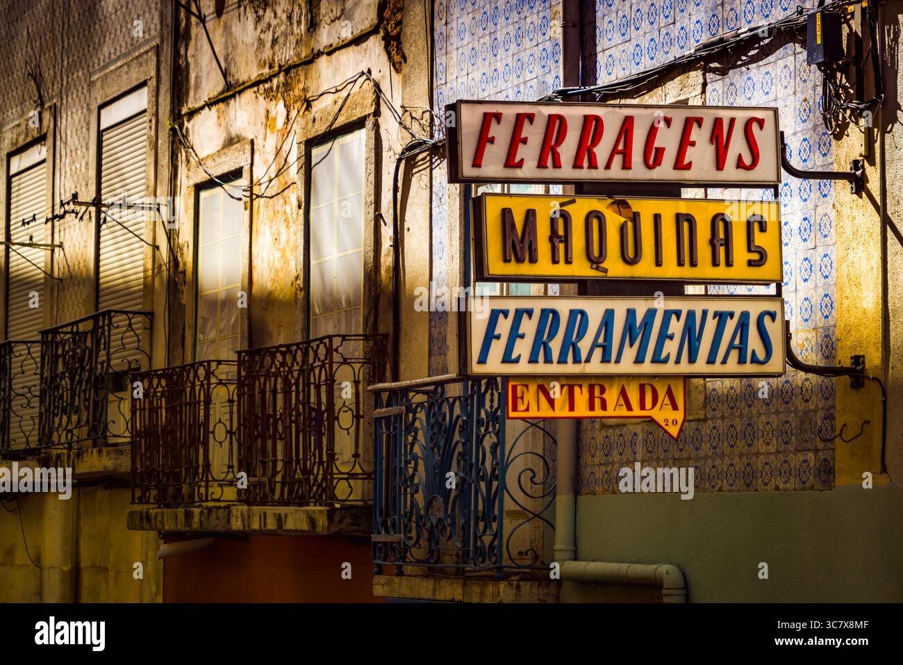 Insegna vintage al neon shop per hardware e macchine su una facciata di un edificio intempestivo a Lisbona, Portogallo, con piastrelle azulejos e balconi in ferro. Foto Stock