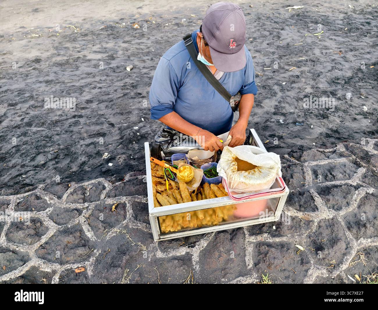 Un venditore ambulante che prepara il Lumpiang Pincuk, un tradizionale spuntino balinese con involtini primavera fritti e frittelle Foto Stock