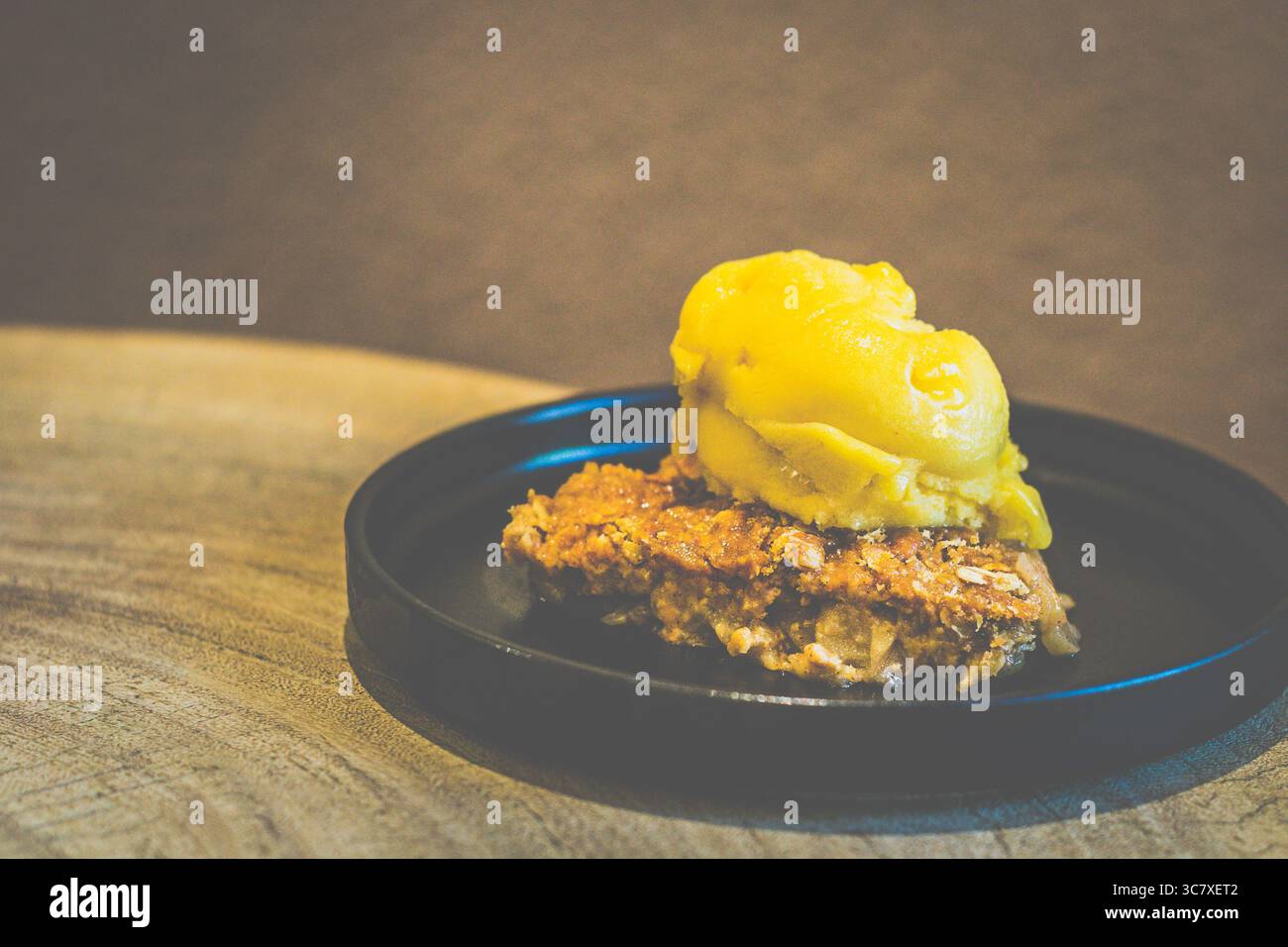 Crumble di mele con crumble di mele al sorbetto di mango Granny Smith con ripieno caldo e speziato e un top croccante, servito con sorbetto al mango Foto Stock