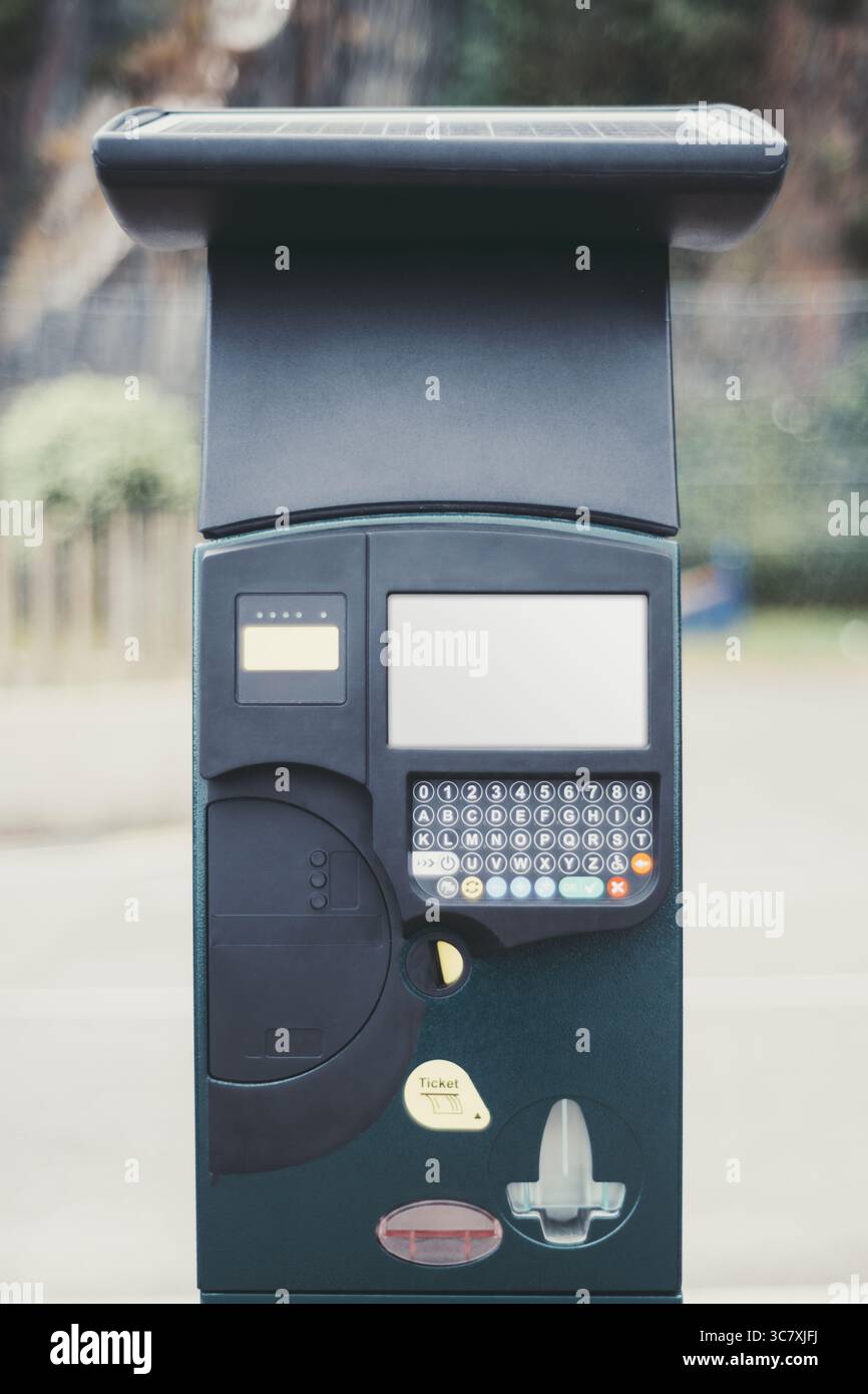 Moderno parchimetro a energia solare con tastiera, display digitale e distributore di biglietti, in piedi su una strada con sfondo urbano sfocato, offerta Foto Stock