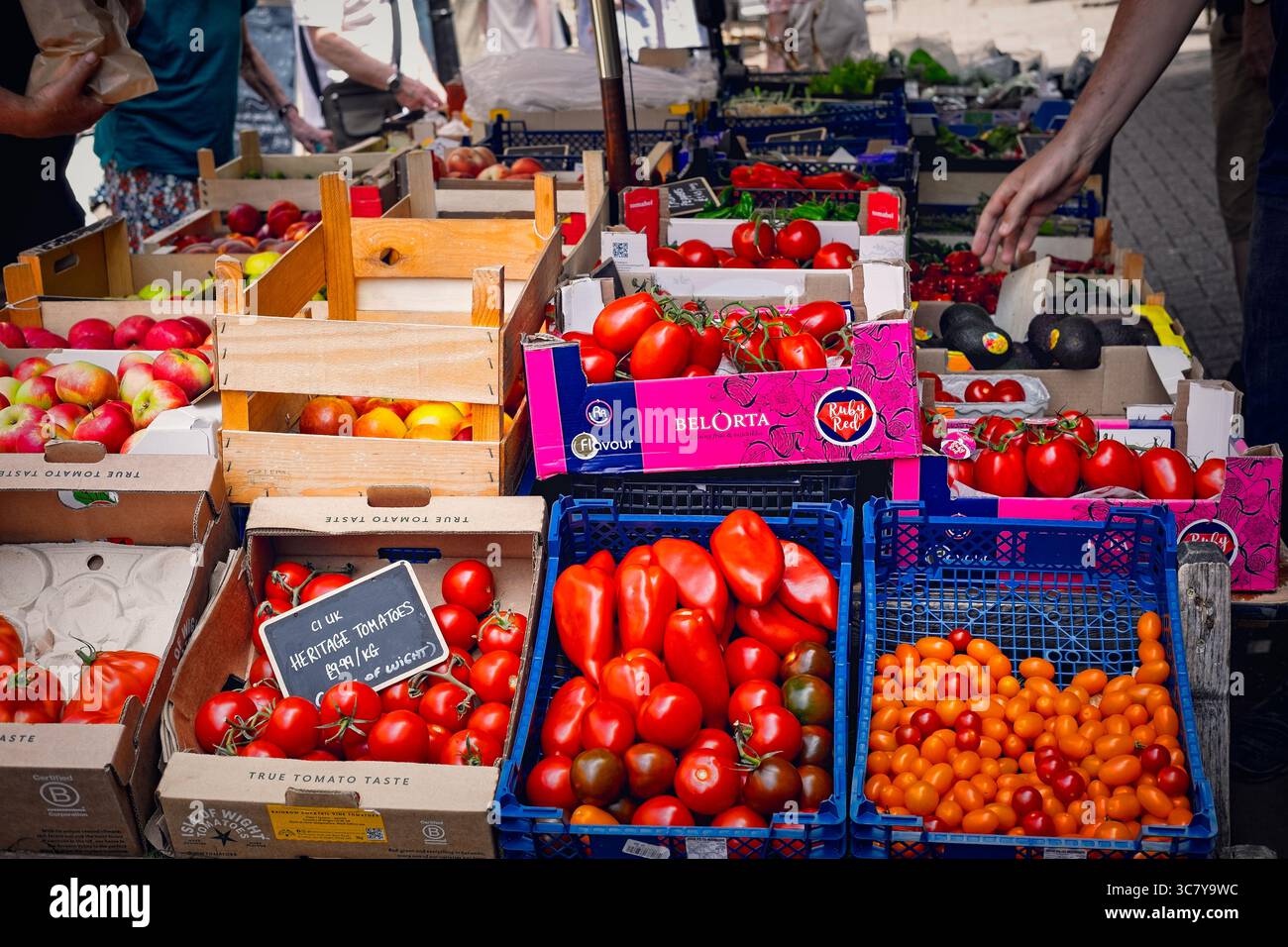 Prodotti freschi in un mercato agricolo. Pomodori colorati, mele e altri tipi di frutta e verdura in esposizione. Foto Stock