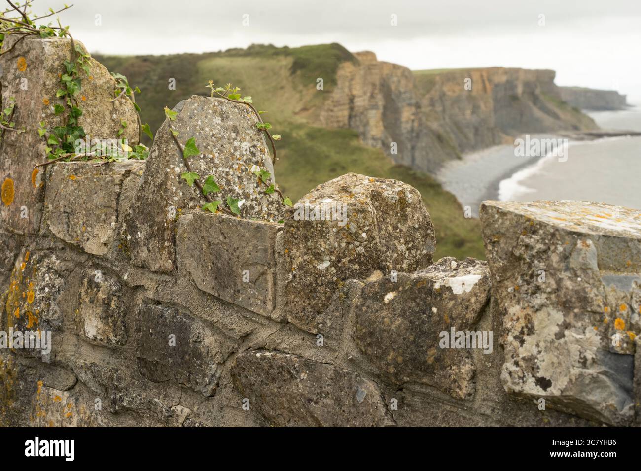 Un muro di pietra si affaccia sulle scogliere della Jurassic Coast. Il muro fornisce un elemento in primo piano, incorniciando il suggestivo paesaggio costiero. Foto Stock