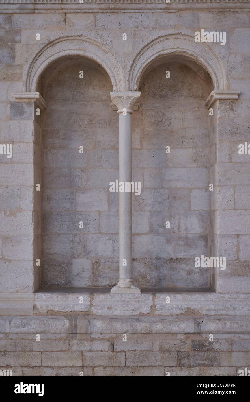 Due archi arrotondati separati da colonne in pietra intagliata con capitale decorativo. Dettagli architettonici romanici classici in pietra calcarea. Foto Stock