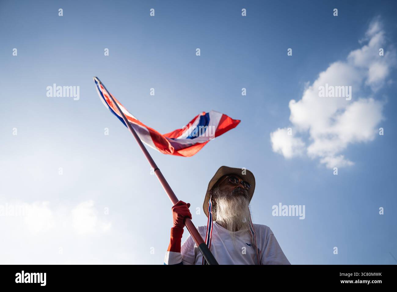 Bangkok, Thailandia. 2 agosto 2025. Un manifestante alza la bandiera nazionale thailandese durante una protesta anti-governativa. I manifestanti si sono riuniti al Victory Monument di Bangkok chiedendo le dimissioni del primo ministro Paetongtarn Shinawatra, citando le tensioni di confine con la Cambogia e il suo verdetto della Corte costituzionale in attesa di approvazione. Credito: SOPA Images Limited/Alamy Live News Foto Stock