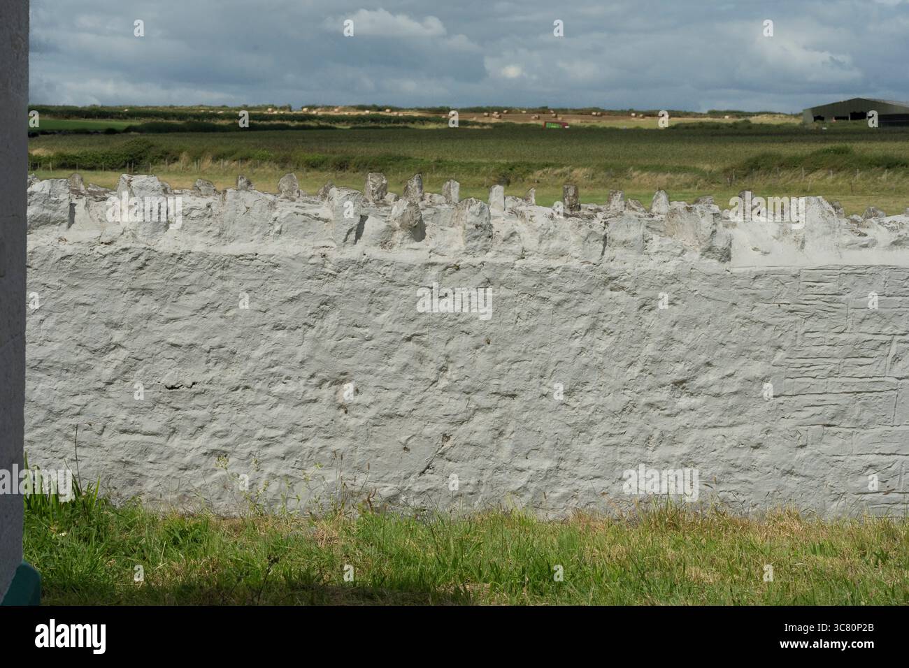 Un muro di pietra si trova di fronte a un campo vicino a Nash Point Foto Stock