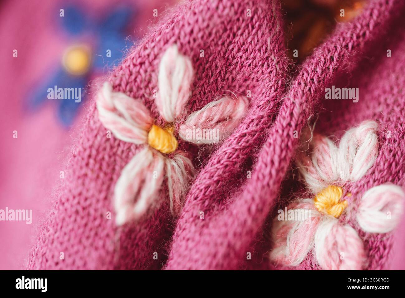 Primo piano del ricamo floreale su un pullover in lana rosa fatto in casa Foto Stock