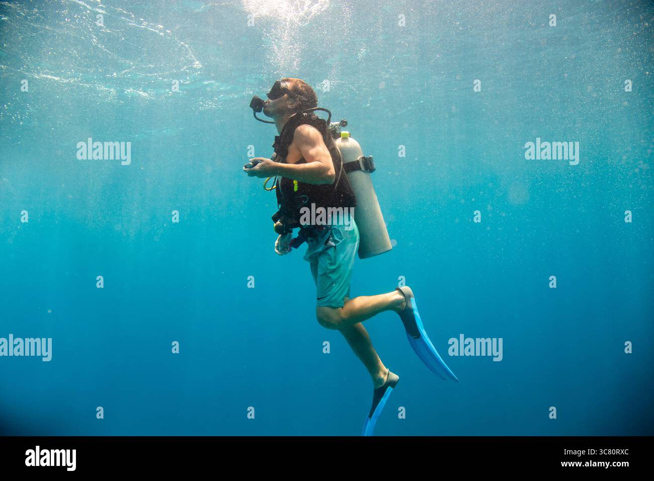 Vista laterale di un uomo in bauli da nuoto immersioni subacquee con un'aqualung, pinne e maschera subacquea Foto Stock