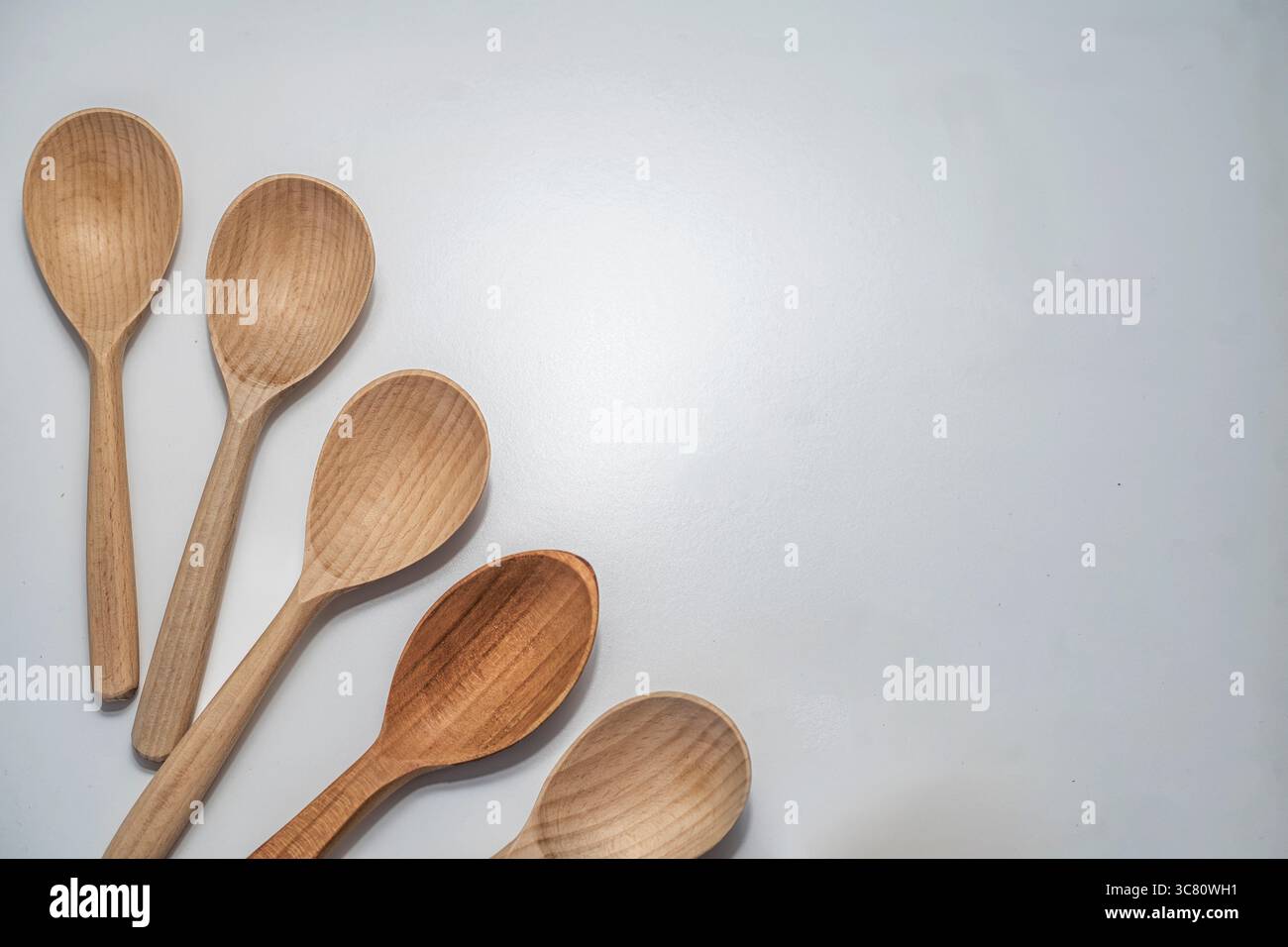 Cinque cucchiai di legno disposti su sfondo bianco. Utensili da cucina rustici e naturali per cucinare, servire e uno stile di vita ecologico. Foto Stock