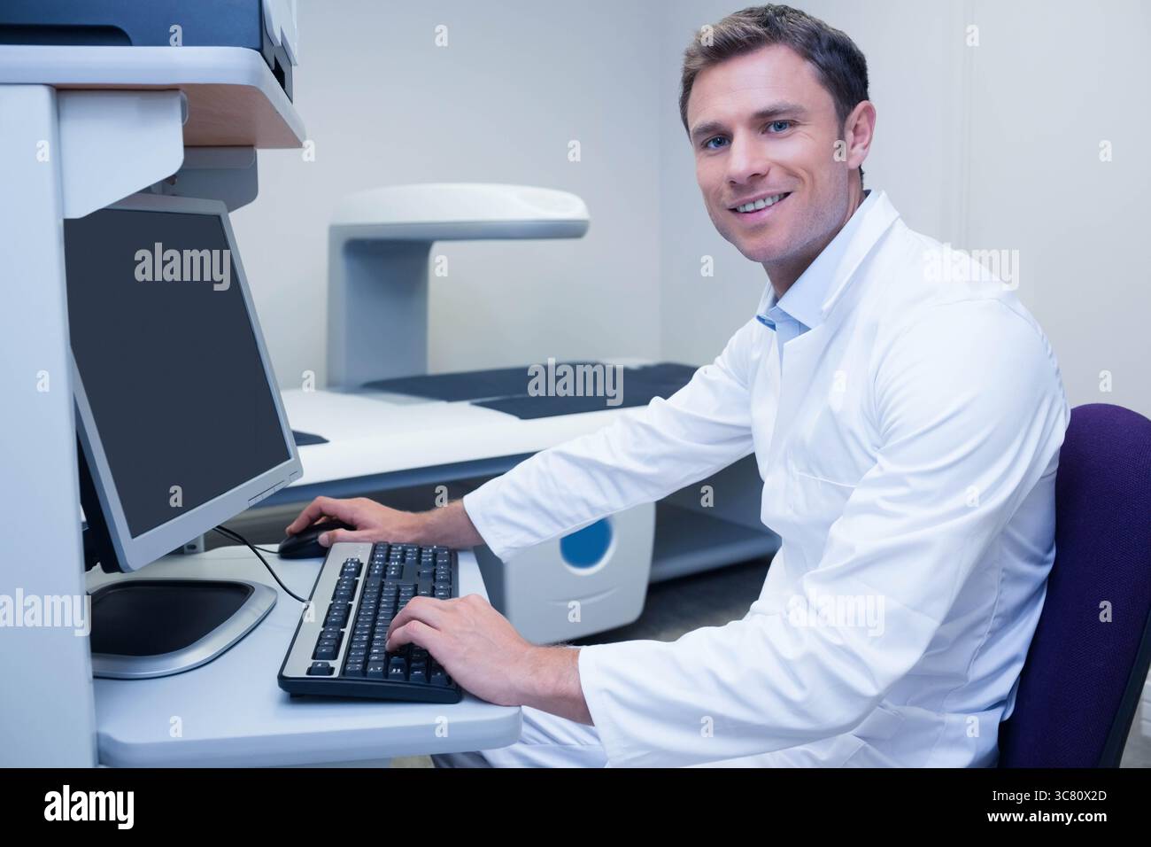 Scanner per imaging medicale a schermo piatto che funziona accanto al mouse sulla scrivania sotto una luce clinica intensa Foto Stock