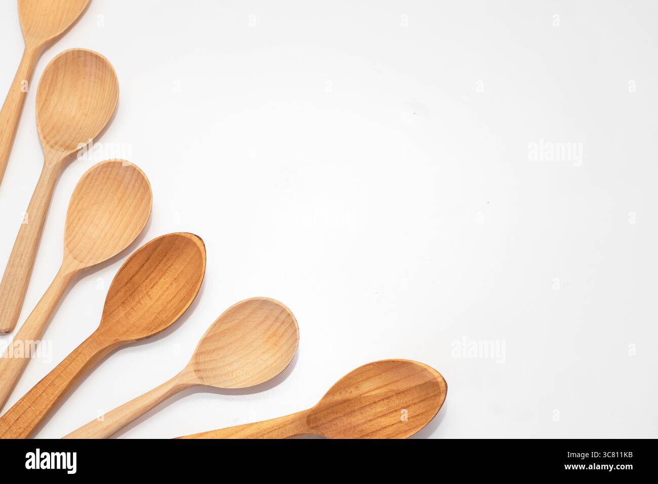 Cinque cucchiai di legno disposti su sfondo bianco. Utensili da cucina rustici e naturali per cucinare, servire e uno stile di vita ecologico. Foto Stock