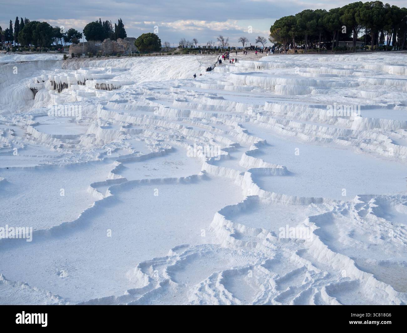 I turisti esplorano le travertini di Pamukkale in Turchia, una meraviglia naturale formata da acque termali ricche di minerali, che attirano i visitatori per il suo paesaggio unico e il suo significato storico. Foto Stock