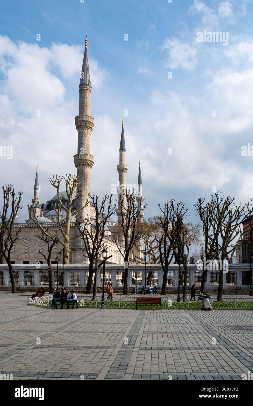 Le persone sono sedute e camminano intorno alla Moschea Blu di Istanbul, in Turchia, ammirando il paesaggio e l'atmosfera del sito storico. Foto Stock