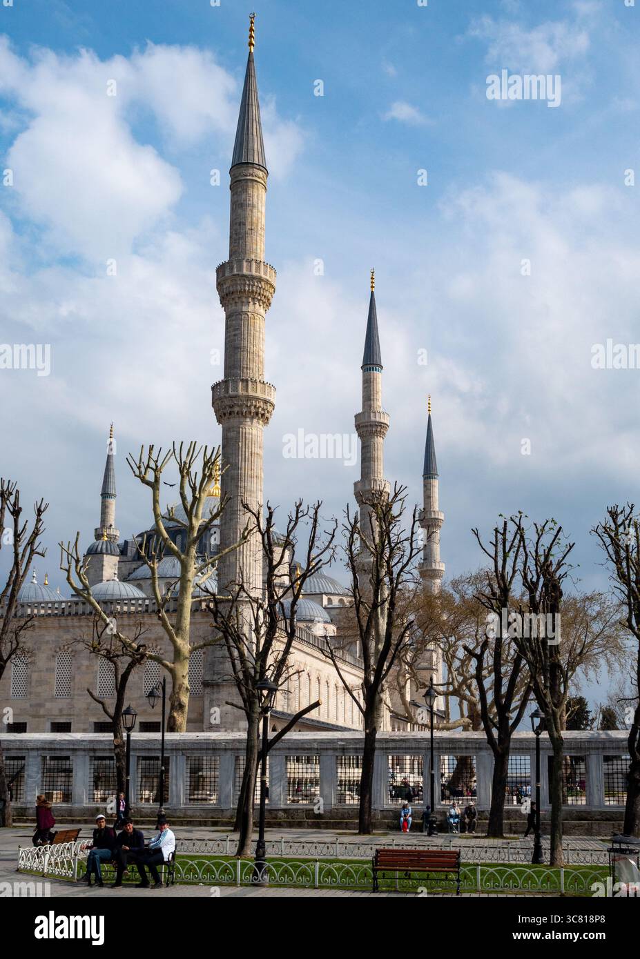 Le persone si rilassano sulle panchine in un parco di fronte alla Moschea Blu di Istanbul, Turchia, godendosi il paesaggio e il clima piacevole. Foto Stock
