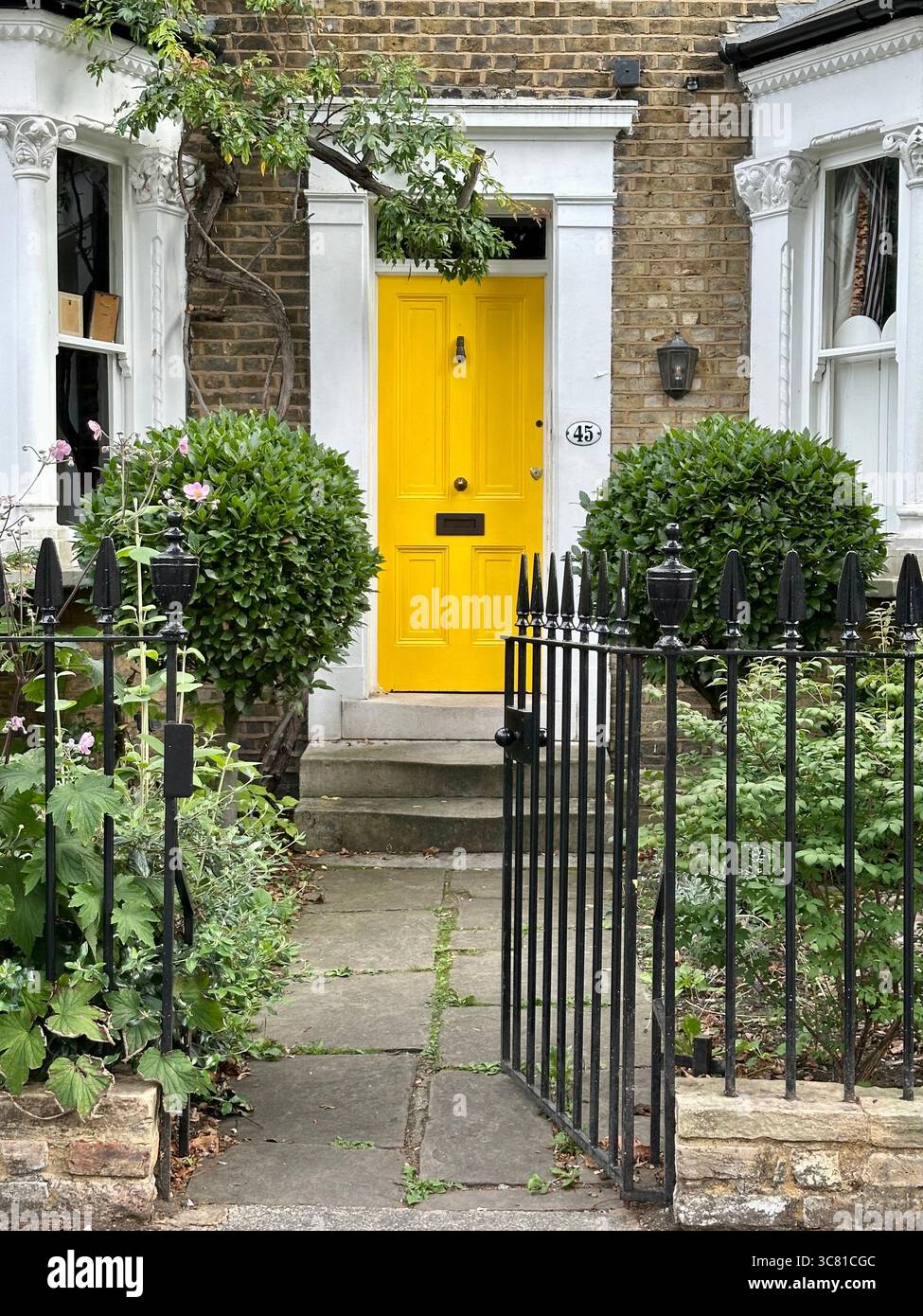 Una porta gialla in un edificio in mattoni a Peckham, Londra - Immagine stock catturata con smartphone
