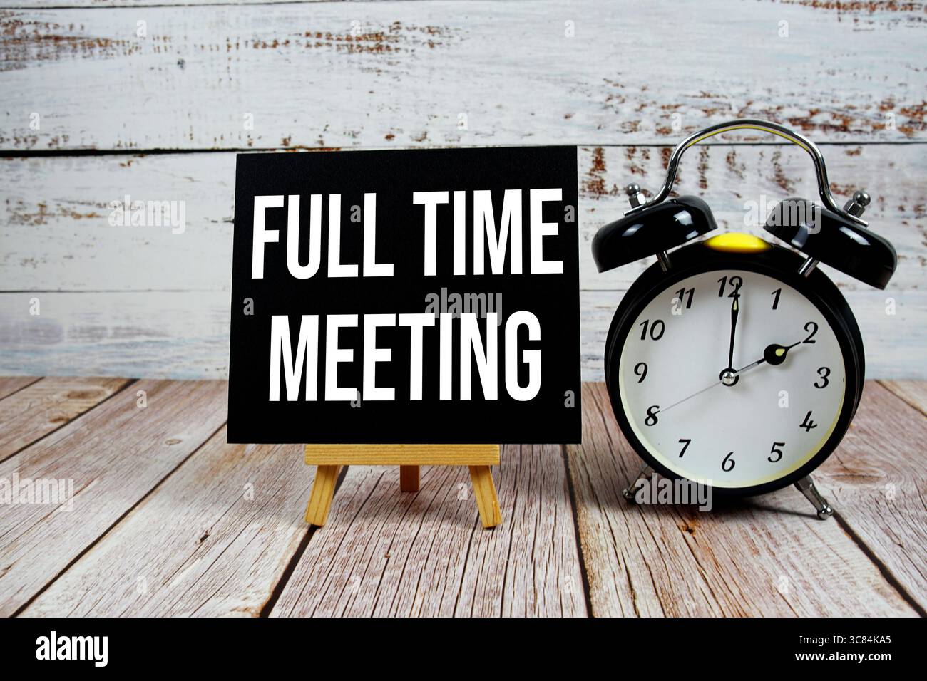 Testo per riunioni a tempo pieno con cavalletto e sveglia su sfondo in legno Foto Stock