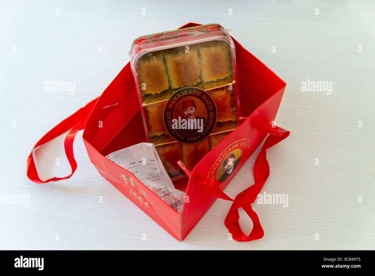 Lubiana, Slovenia –30.07.2025: Scatola di baklava tradizionale turco del famoso marchio Hafiz Mustafa 1864 in una borsa regalo di marca rossa Foto Stock