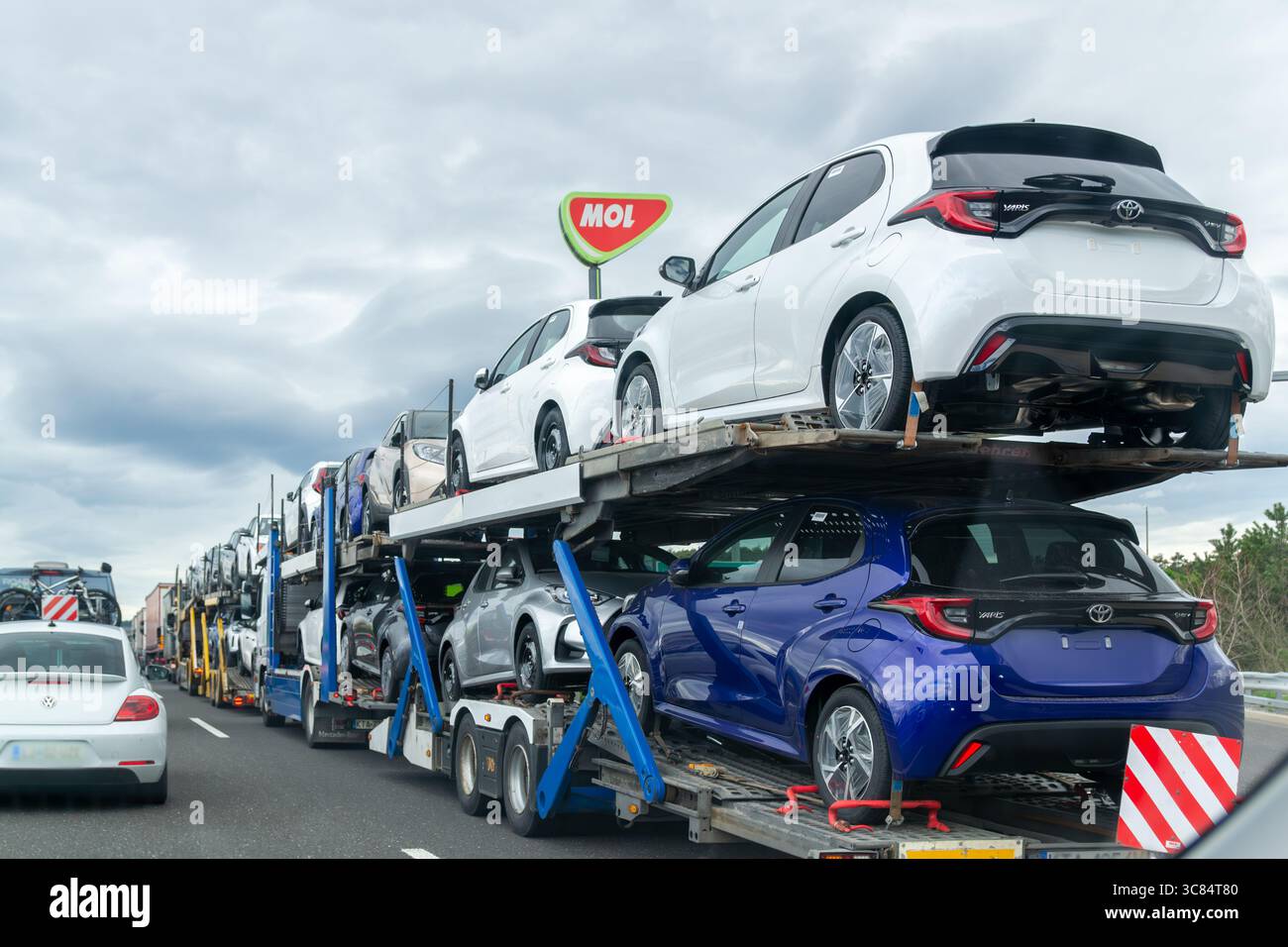 Kozina, Slovenia- 25.04.2025: Autocarro che trasporta nuovi veicoli Toyota in autostrada, vista posteriore del rimorchio per il trasporto di auto con auto compatte Foto Stock