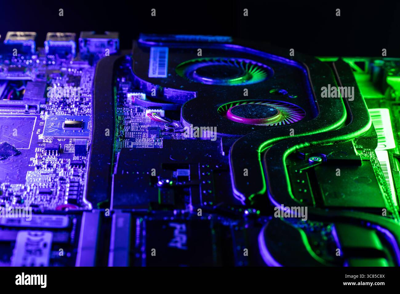 Primo piano di un sistema di raffreddamento GPU ad alte prestazioni con due ventole sotto una spettacolare illuminazione blu e verde Foto Stock