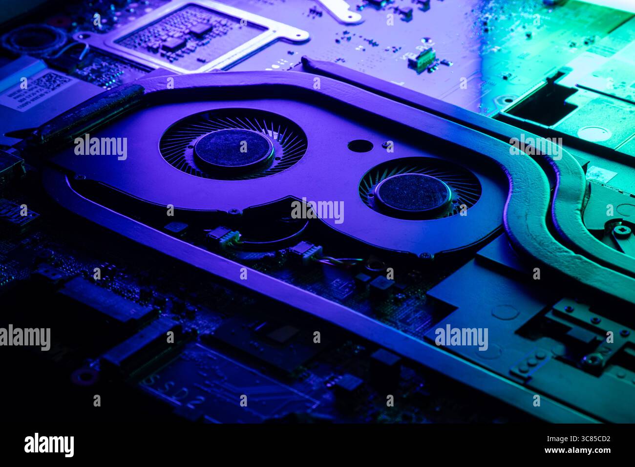 Primo piano di un sistema di raffreddamento GPU ad alte prestazioni con due ventole sotto una spettacolare illuminazione blu e verde Foto Stock