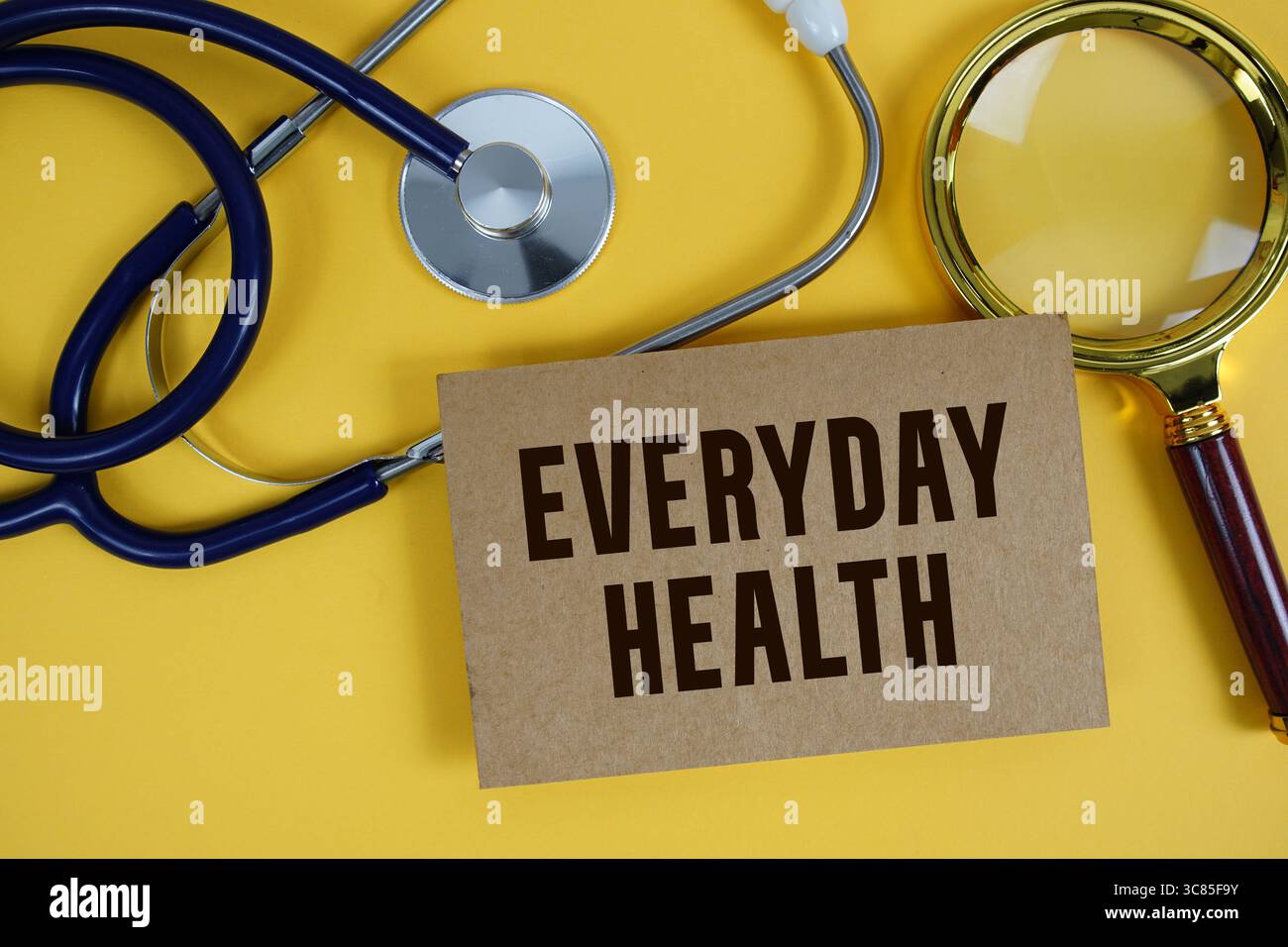 Testo di salute quotidiana su scheda di carta con stetoscopio piatto giacente su sfondo giallo Foto Stock