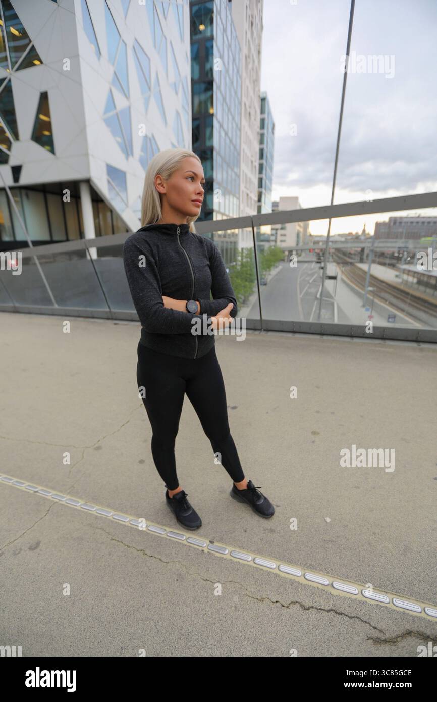 Allenati in città con una donna sicura di sé in piedi all'aperto in città Foto Stock