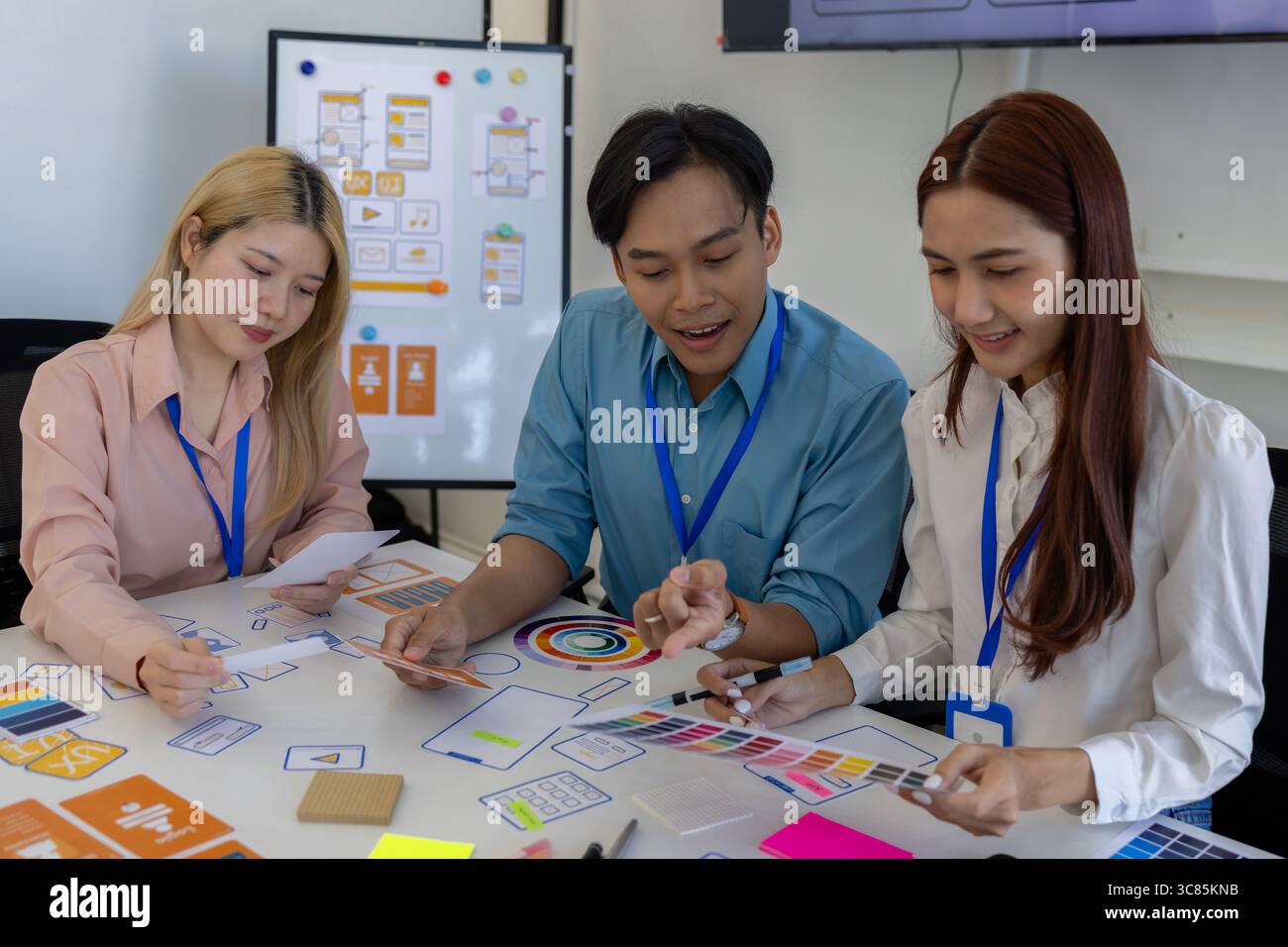 i progettisti di ux, ui, web e app mobili stanno discutendo dell'aspetto del sito web o dell'app che stanno progettando, inclusi schemi di colori e layout Foto Stock