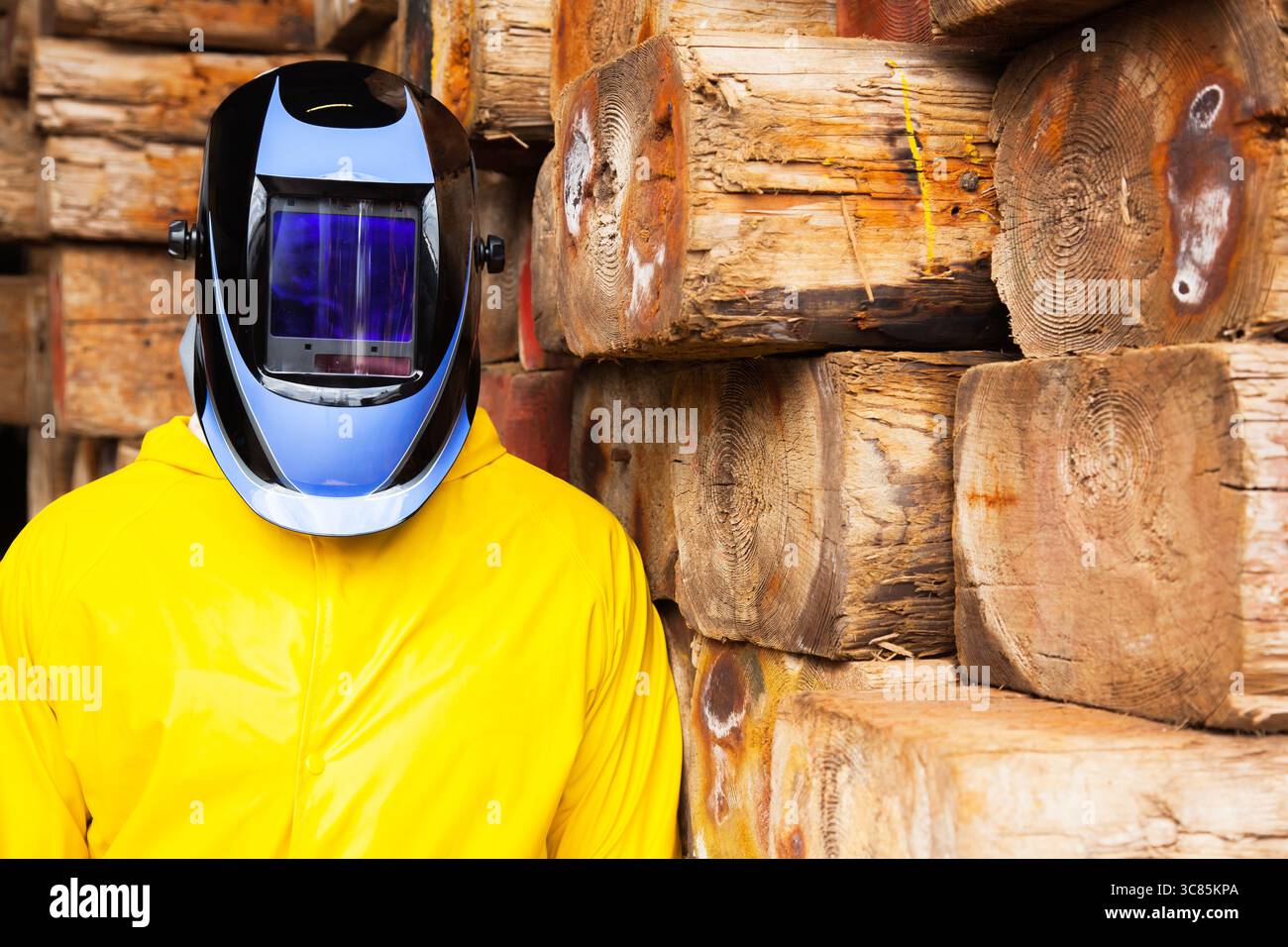 Un uomo con una tuta chimica protettiva e una maschera di saldatura sulla testa. Foto Stock