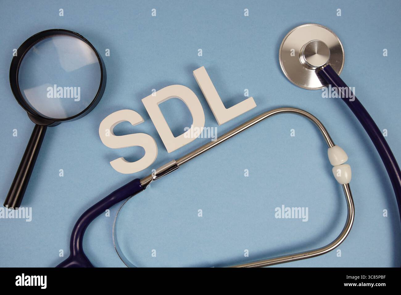 Lettere alfabetiche SDL Self-Directed Learning con stetoscopio e lente di ingrandimento su sfondo blu Foto Stock