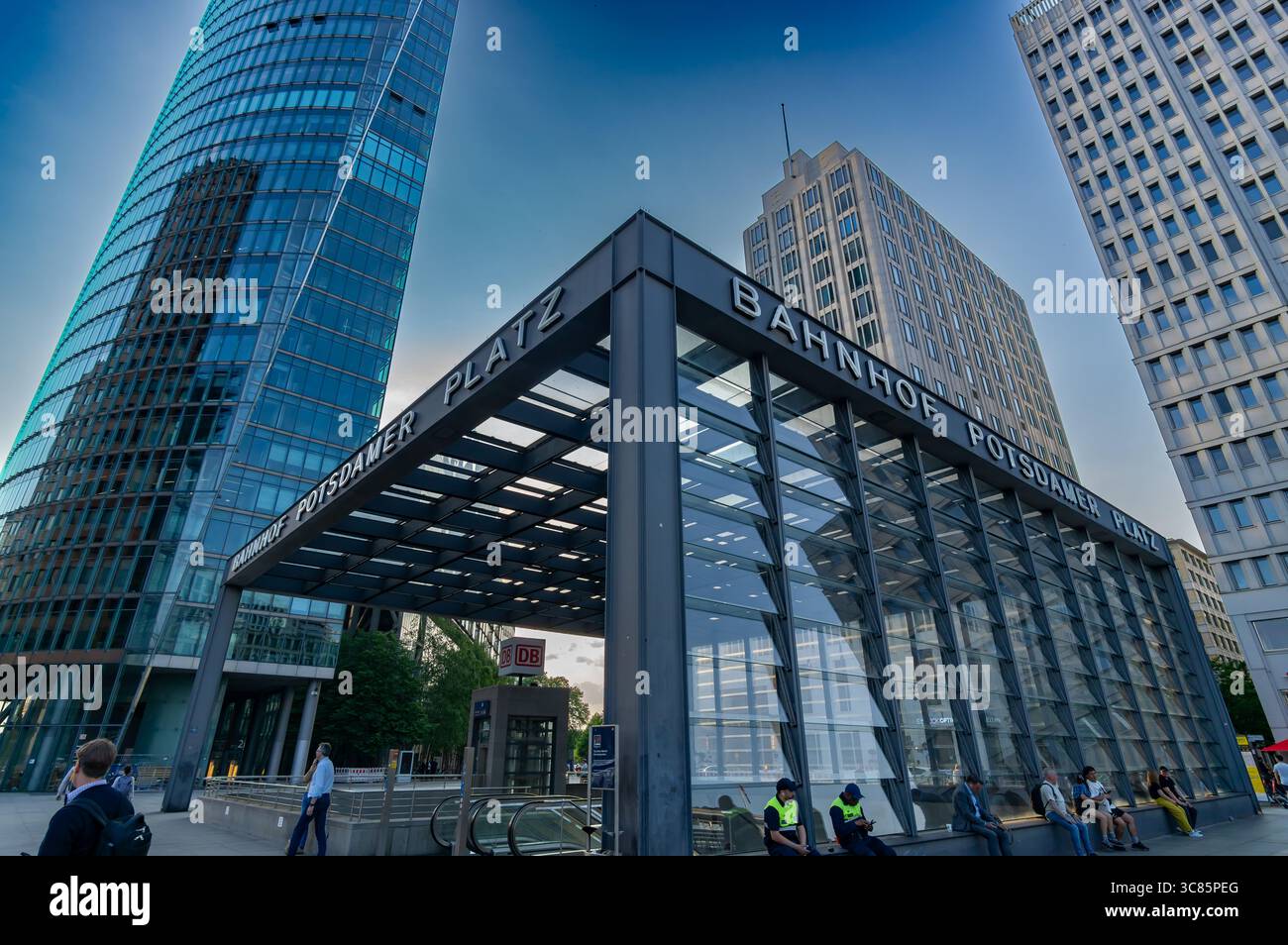 Moderna entrata in vetro della stazione di Berlins Potsdamer Platz (Bahnhof Potsdamer Platz), fiancheggiata da grattacieli e affollato traffico pedonale in perfetta simmetria. Foto Stock