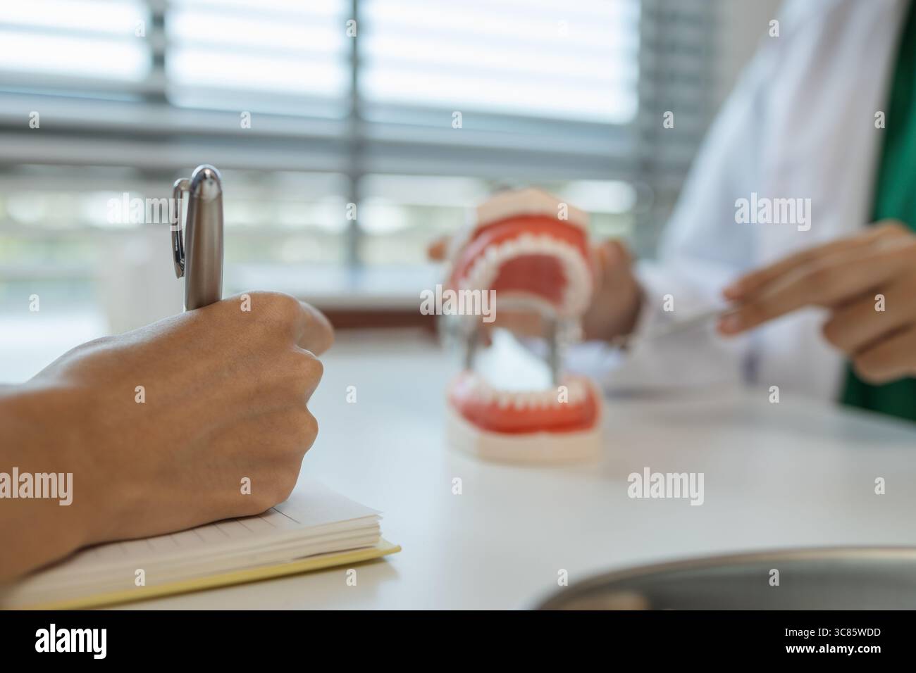 il dentista sta sta spiegando all'assistente come tratterà un paziente con saggezza dei denti, i due dentisti hanno discusso il piano di trattamento per la paziente Foto Stock