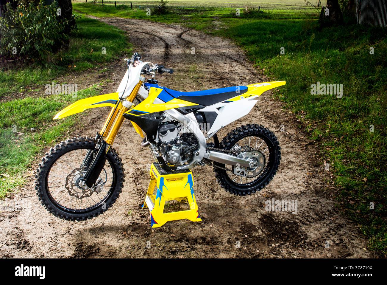 Una potente moto da motocross poggia sul suo supporto su un sentiero rurale fangoso. Questa immagine cattura perfettamente lo spirito dell'avventura fuoristrada. Foto Stock