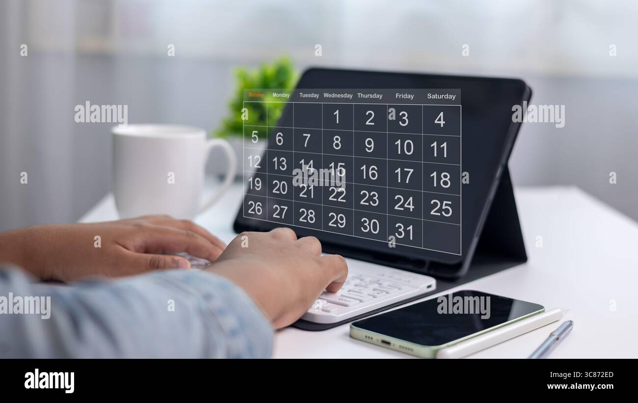 Pianificazione di una persona organizzata con l'app calendario digitale su tablet, con smartphone, tastiera e tazza di caffè sullo spazio di lavoro moderno, concetto di tempo Foto Stock