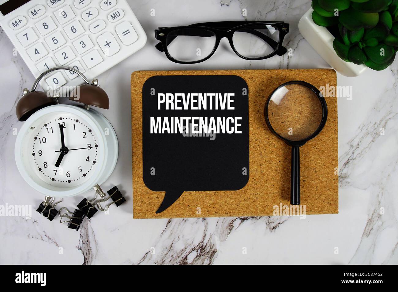 Testo manutenzione preventiva con calcolatrice, sveglia e lente di ingrandimento su sfondo in marmo Foto Stock