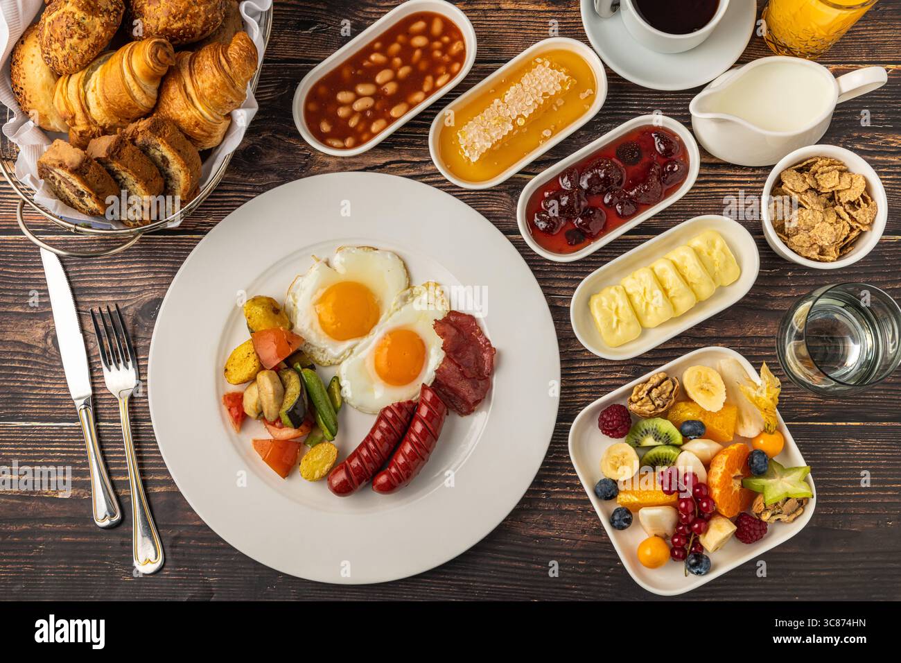 Colazione inglese tradizionale con uova, fagioli, salsiccia e frutta fresca Foto Stock