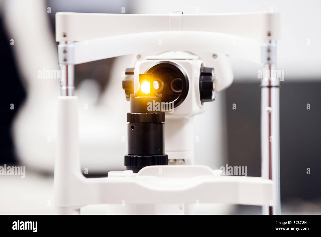 Moderna apparecchiatura a fessura con lente illuminata, progettata per esami oculistici e diagnostica, che mette in risalto la tecnologia avanzata in un ambiente clinico Foto Stock