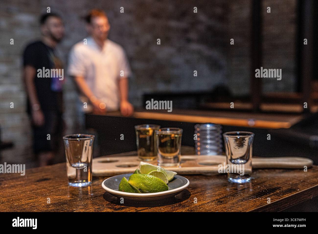 Svuotate i bicchieri di tequila con spicchi di lime su un tavolo di legno in un bar, resti di una serata fuori. Vista ravvicinata per catturare l'atmosfera dopo gli scatti. Foto Stock