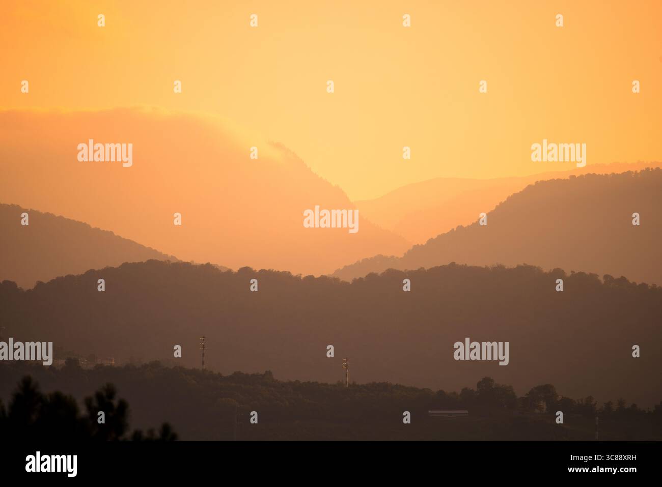 L'alba dorata sugli strati nebbiosi delle montagne crea un paesaggio tranquillo e suggestivo con la calda luce del mattino. Foto Stock