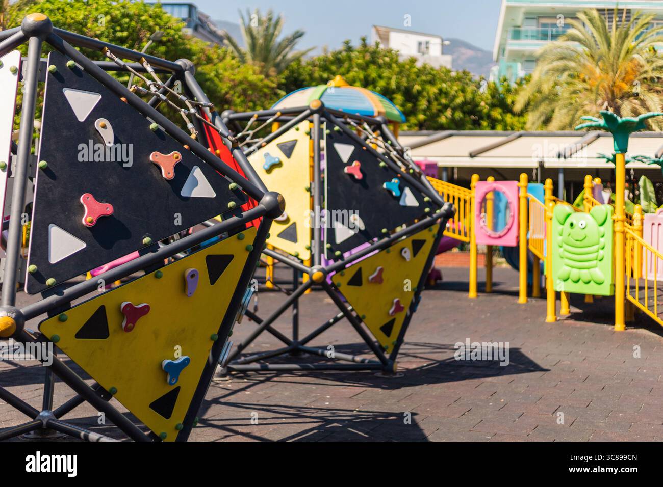 Strutture per arrampicate dai colori vivaci e aree giochi riempiono un parco soleggiato, offrendo ai bambini un luogo divertente per arrampicarsi, esplorare e divertirsi in un gioco fantasioso Foto Stock