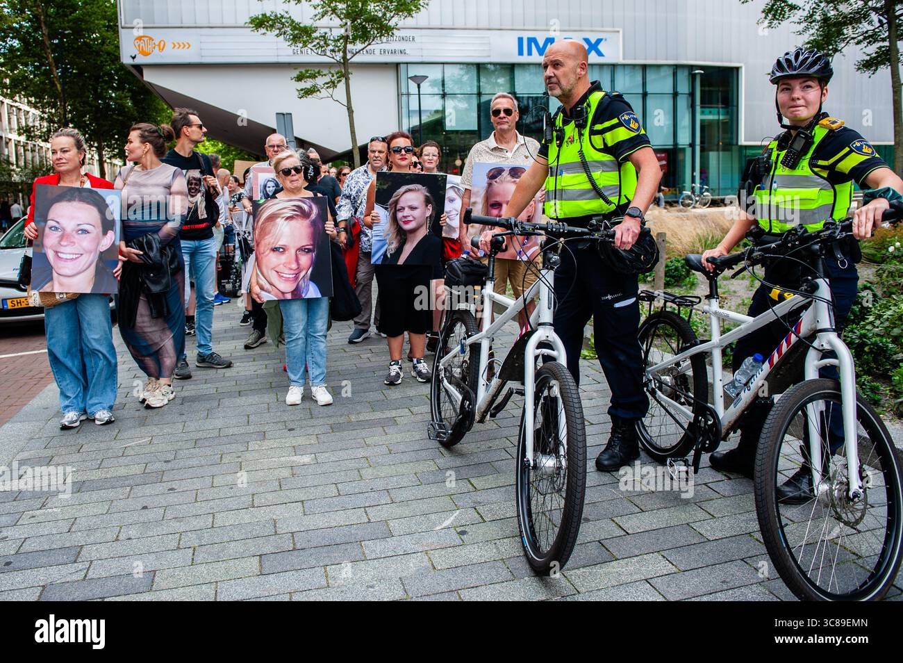 Gli agenti di polizia guidano e proteggono la marcia durante una manifestazione contro il femminicidio a Rotterdam. L'organizzazione femminista olandese "Dolle Mina" ha tenuto una marcia nazionale di protesta contro il femminicidio a Rotterdam. Questo è in risposta a due omicidi di donne in meno di una settimana. In entrambi i casi, il sospetto si è rivelato essere un (ex) partner della vittima. "Dolle Mina" richiede che il femminicidio sia riconosciuto come una "forma specifica e strutturale di violenza basata sul genere". Durante il discorso di uno dei genitori di una delle vittime, un uomo corse sul palco e cercò di interrompere l'evento. Foto Stock