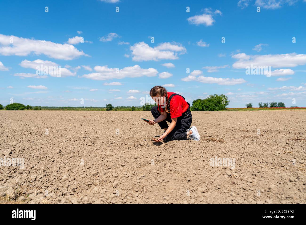 Esperta di agricoltura femminile con telefono cellulare che controlla la salute del suolo per l'agricoltura di precisione e l'agricoltura resiliente al clima Foto Stock Esperta di agricoltura femminile con telefono cellulare che controlla la salute del suolo per l'agricoltura di precisione e l'agricoltura resiliente al clima Foto Stock