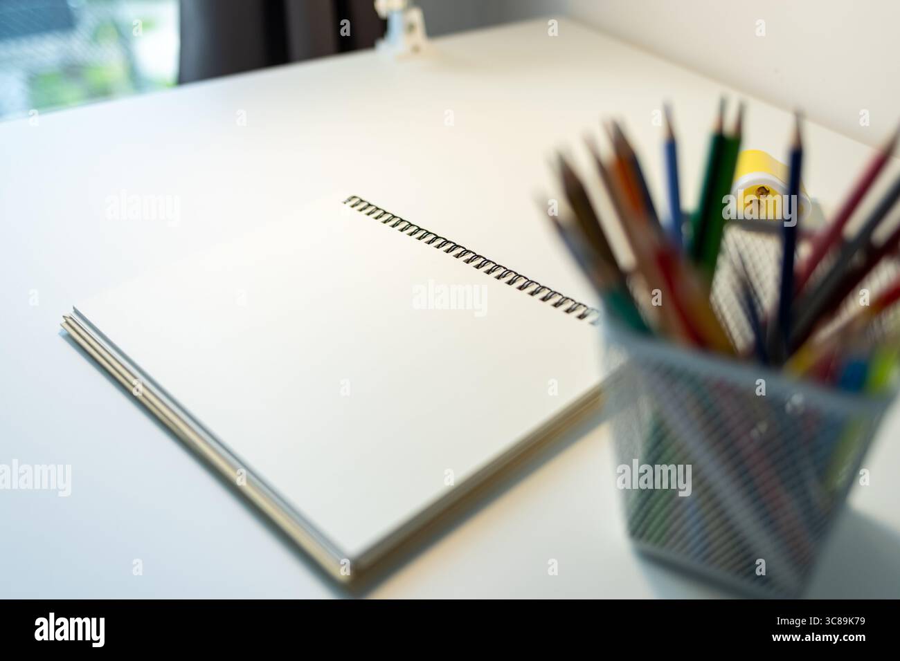 sketchbook illuminato da lampada e set di matite colorate su tavolo, disegno e hobby, concetto di ritorno a scuola Foto Stock